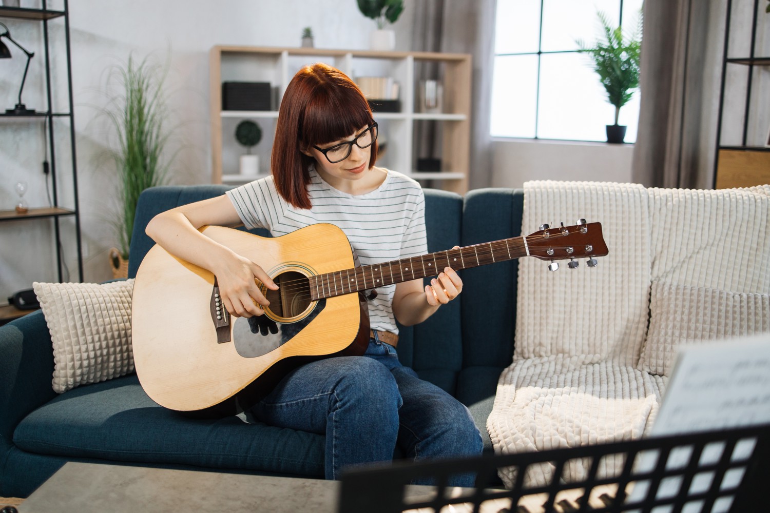 A Young Woman Learning to Play an Acoustic Guitar For Beginners at Home