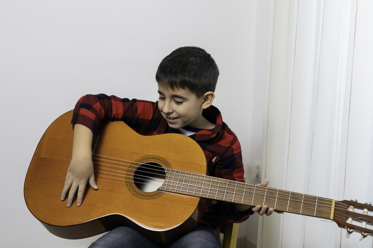 A Young Lad Struggling to Learn to Play a Large Classical Guitar