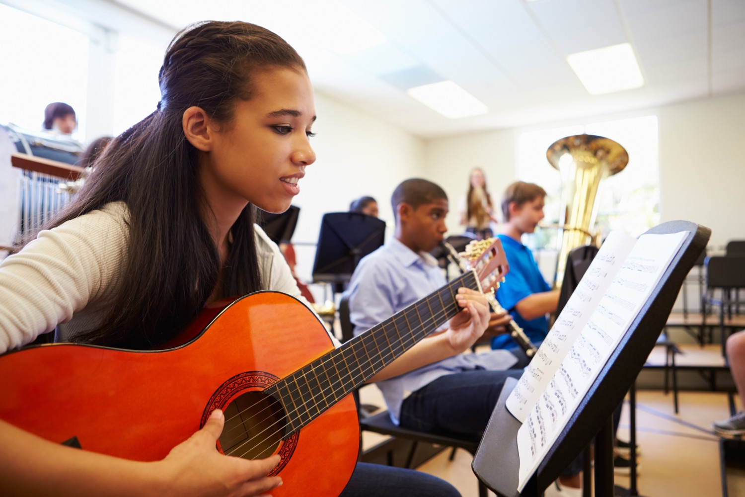 A Student Learning to Play a Small Guitar in a Newly Formed Orchestra at School