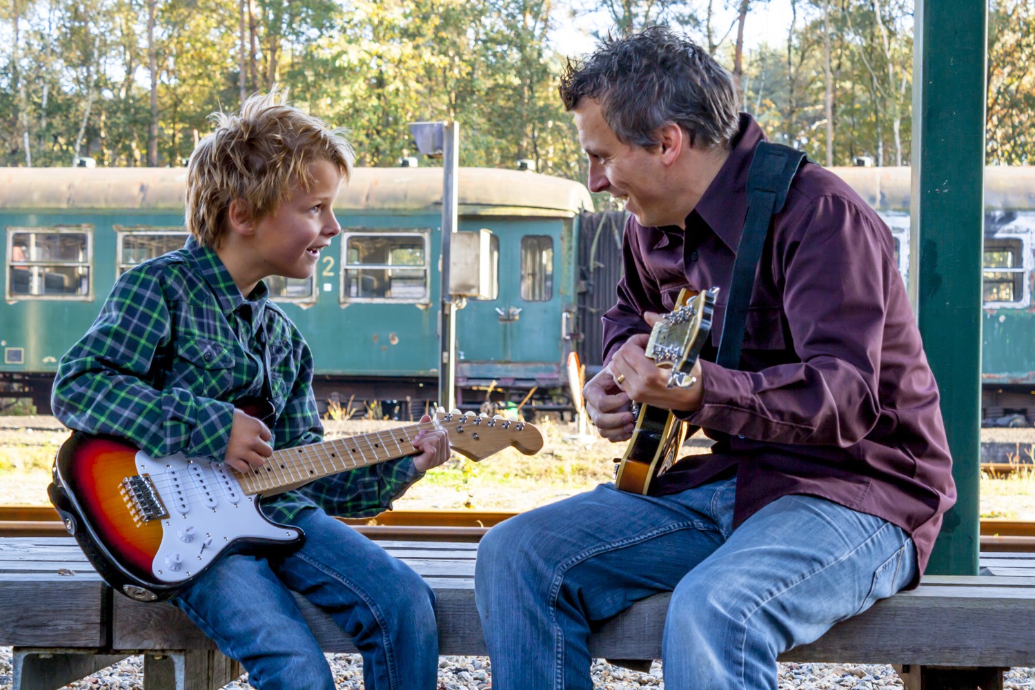 Young Boy Being Taught to Play His First Electric Guitar by His Dad